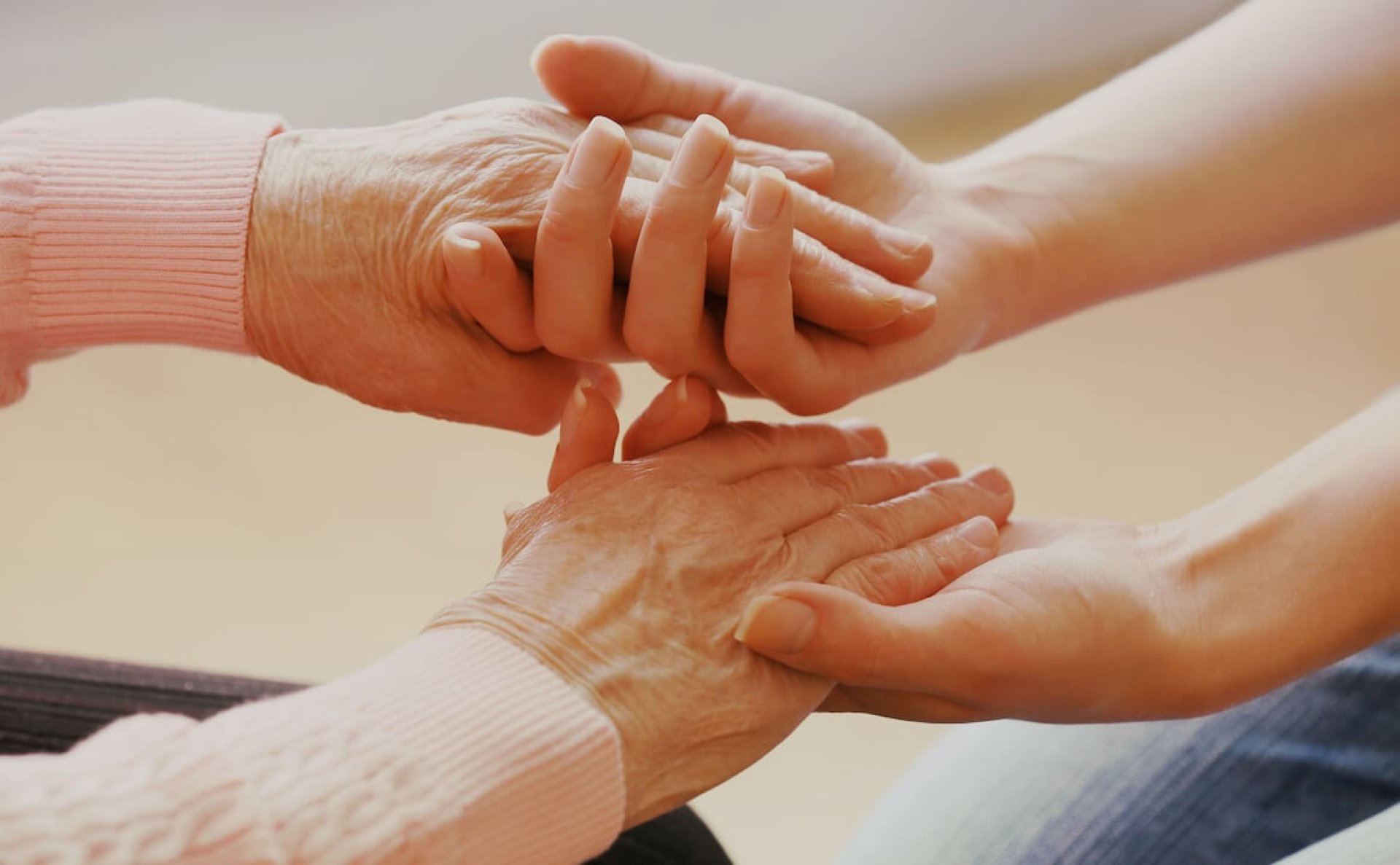 Aide à domicile tenant les mains d'une personne âgée