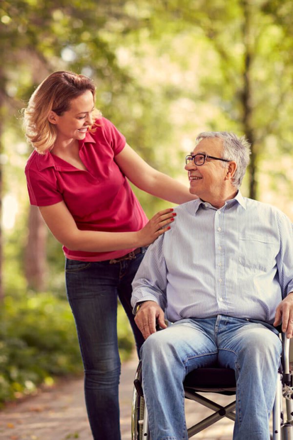 Dame qui s'occupe d'une personne agée en fauteuil roulant